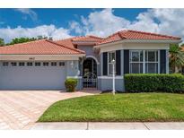 Charming home exterior featuring a terracotta roof, lush greenery, and a brick paved driveway at 5017 Hanging Moss Ln, Sarasota, FL 34238