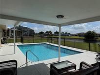 Enjoy outdoor living with this pool, featuring a covered patio and serene water views at 61 Caddy Rd, Rotonda West, FL 33947