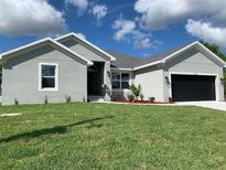 Charming single-story home with a well-manicured lawn, a two car garage, and a welcoming front entrance at 13902 Allamanda Cir, Port Charlotte, FL 33981