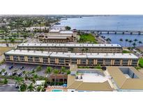 Expansive aerial view of the community with tropical landscaping, pool, parking, and stunning waterfront views at 150 Harborside Ave # 304, Punta Gorda, FL 33950