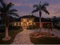 Elegant home featuring lush landscaping, stone driveway, and striking architecture under a twilight sky at 197 Colony Point Dr, Punta Gorda, FL 33950