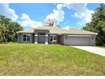 Beautiful single-story home featuring a well-manicured lawn and a two-car garage at 2201 Como St, Port Charlotte, FL 33948