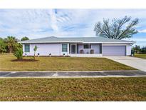 Charming single-story home with a well-maintained lawn, purple paint, and a cozy screened porch at 3940 Abbotsford St, North Port, FL 34287