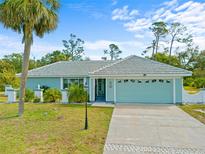 Charming single Gathering home with a two car garage, luscious green yard, and welcoming front entrance at 5126 Richmond Ter, North Port, FL 34287