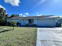 Charming single-story home with light blue paint, an attached garage, and well-maintained landscaping at 1386 Kensington St, Port Charlotte, FL 33952