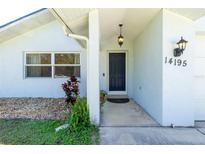 Inviting front entrance with well-kept landscaping, hanging pendant, and clear house number at 14195 Brisk Ave, Port Charlotte, FL 33953