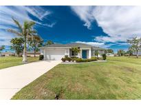 Charming single-story home featuring a well-manicured lawn, a bright blue front door and a spacious two car garage at 16271 Branco Dr, Punta Gorda, FL 33955