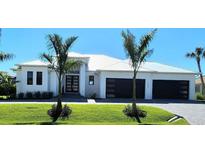 Beautiful new construction home with a metal roof, three-car garage, and lush landscaping with palm trees at 1631 Casey Key Dr, Punta Gorda, FL 33950
