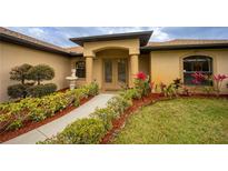 Inviting front entrance with double doors, manicured landscaping, and a charming fountain feature at 17327 Wintergarden Ave, Port Charlotte, FL 33948