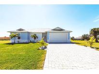 Charming single-story home with a well-manicured lawn, brick driveway and beautiful tropical landscaping at 24473 San Rafael Rd, Punta Gorda, FL 33955