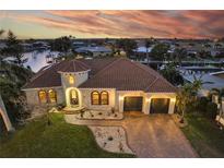 Stunning waterfront home with a tile roof, brick driveway, and a two-car garage at sunset at 257 Lido Dr, Punta Gorda, FL 33950