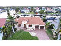 Beautiful Mediterranean home featuring tile roof, arched windows, and lush landscaping with waterway access at 257 Lido Dr, Punta Gorda, FL 33950