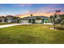 Charming single-story home with well-manicured lawn, tropical landscaping, and an American flag at 321 Pessoa St, Punta Gorda, FL 33983