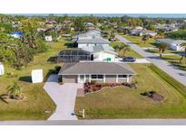 Aerial view of house with well-maintained landscaping, screened-in lanai, and a well-kept lawn at 346 Cypress Nw Ave, Port Charlotte, FL 33952