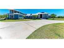 Stunning two-story blue home featuring a grand entrance and a circular driveway at 5755 Riverside Dr, Punta Gorda, FL 33982