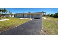 Charming single-story home featuring a well-manicured lawn and long, paved driveway leading up to the entrance at 165 Cummins Ne Ave, Port Charlotte, FL 33952