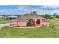 Charming single-story home with well-manicured lawn and bright red front door at 26389 Villa Maria Dr, Punta Gorda, FL 33983