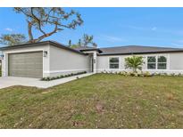 Charming single-story home with a lush green lawn, a two-car garage, and manicured landscaping at 267 Camrose St, Port Charlotte, FL 33954