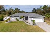 Charming single-story home with a well-manicured lawn, stone landscaping, and a paved driveway leading to the garage at 4373 Atwater Dr, North Port, FL 34288