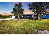 Charming single-story home featuring mature trees, a front lawn, and a driveway leading to the garage at 628 Tarpon Way, Punta Gorda, FL 33950