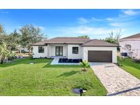 Charming single-story home with a well-manicured lawn, a paved driveway, and a two-car garage at 14319 Allensworth Ave, Port Charlotte, FL 33981
