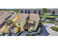 Inviting two-story yellow townhouse with a brick driveway, an attached garage, and waterway access with boats at 25188 Marion Ave # 1015, Punta Gorda, FL 33950