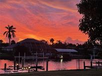 Stunning waterfront property featuring a dock and boat lift under a beautiful vivid sunset at 4091 Rock Creek Dr, Port Charlotte, FL 33948