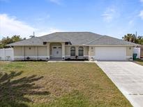 Charming single-story home featuring a well-maintained lawn, double door entrance, and attached two-car garage at 7095 Beardsley St, Englewood, FL 34224