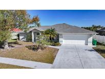 Charming single-story home with a well-manicured lawn, mature trees, and a two-car garage at 13632 Clara Ln, Port Charlotte, FL 33981