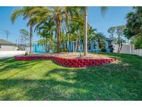 Charming blue home surrounded by lush palms, and a well-maintained lawn, creating a tropical paradise at 1563 Arundel Ave, North Port, FL 34288