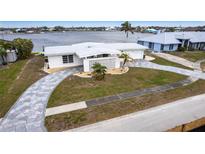 Waterfront home featuring a patterned driveway, white exterior, palm trees, and a water view at 168 Morgan Se Ln, Port Charlotte, FL 33952