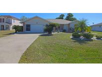 Charming home features a well-maintained lawn with tropical landscaping and a two-car garage at 32 Bariloche Dr, Punta Gorda, FL 33983