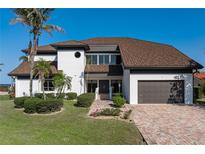 Beautiful two-story home with a well-manicured lawn, brick driveway, and attached two car garage at 8 Ocean Dr, Punta Gorda, FL 33950