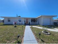 Charming single-story home with a well-manicured lawn and inviting walkway leading to the front door at 858 Conreid Ne Dr, Port Charlotte, FL 33952