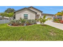 Charming home featuring an attached garage and a manicured lawn with tropical landscaping at 1353 Newton St, Port Charlotte, FL 33952