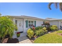 Charming single-story home featuring a well-maintained lawn and landscaping with palm trees at 196 The Corso # 196, Venice, FL 34285