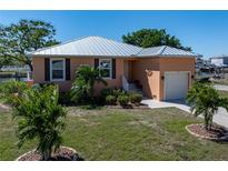 Charming waterfront home featuring a durable metal roof, lush landscaping, and a convenient one-car garage at 721 Dania Ct, Punta Gorda, FL 33950