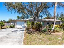 Charming single-story home featuring a lush front yard and a large driveway leading to an attached garage at 1516 Saint Clair Rd, Englewood, FL 34223