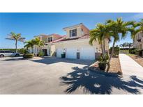Inviting exterior view of townhomes featuring multiple garages and lush palm trees under a clear blue sky at 17200 Acapulco Rd # 123, Punta Gorda, FL 33955