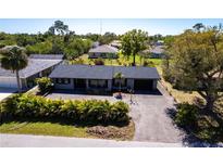 Aerial view of a single story home featuring a driveway and manicured landscaping in a lush neighborhood at 23179 Maclellan Ave, Port Charlotte, FL 33980