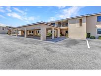 Condo building featuring covered parking, beige exterior, and well-maintained landscaping at 240 Lewis Cir # 28, Punta Gorda, FL 33950