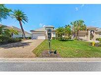 Beautiful home featuring a well-manicured lawn, brick driveway and mature palm trees in desirable community at 13352 Creekside Ln, Port Charlotte, FL 33953