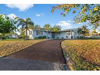 Charming single-story home featuring a long driveway, well-maintained lawn, and beautiful mature landscaping at 146 Francis Ne Dr, Port Charlotte, FL 33952