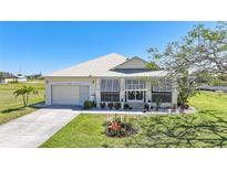 Charming single-story home featuring lush landscaping, a well-maintained lawn, and a metal roof at 17408 Malarky Ln, Punta Gorda, FL 33955