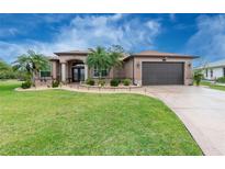 Charming single-story home with manicured lawn, tropical landscaping, and covered front entry at 21 Manizaks Ave, Punta Gorda, FL 33983