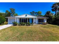 Charming single-story home with a well-manicured lawn and a bright blue front door at 410 Hinton St, Port Charlotte, FL 33954