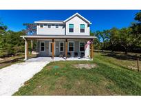 Charming two-story home with a welcoming front porch, gray siding, and an American flag at 14289 Manatee Rd, Parrish, FL 34219