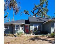 Charming single-story home featuring a red front door and a well-manicured lawn at 17056 Doyle Ave, Port Charlotte, FL 33954