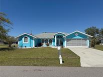 Charming blue single-story home featuring a well-manicured lawn and a gray roof with white trim at 25472 Tevesine Ct, Punta Gorda, FL 33983