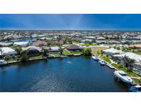 Aerial view showcasing a waterfront community with homes, canals, and boat docks under a clear blue sky at 3606 Whippoorwill Blvd, Punta Gorda, FL 33950